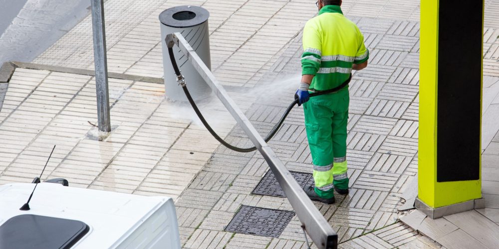 Worker cleaning a street sidewalk with water